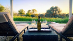 A lounge area with two chairs, a table, and a bottle of wine. - Luxury private condo for 2 w/pool in Apulian hills. Only 15 mins from beach! (Puglia)