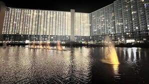 Un grande hotel con un elemento d'acqua riflettente nella facciata, illuminato da luci.