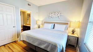 Una camera da letto con un letto, un comodino, un addobbo a parete e una porta.