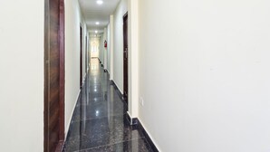 Un lungo e stretto corridoio con pavimento lucido, pareti bianche e porte su entrambi i lati.