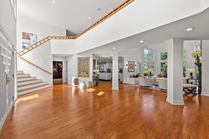 A spacious interior with a wooden staircase, a dining area, and a living room with a view of the outdoors. - Private 1-Acre 6BR Luxury Estate - FIFA World Cup 20min to MetLife Stadium & NYC (Cresskill)
