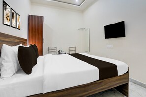 A modern hotel room with a large bed, a flat-screen TV, a mirror, and a door with a vertical wooden panel.