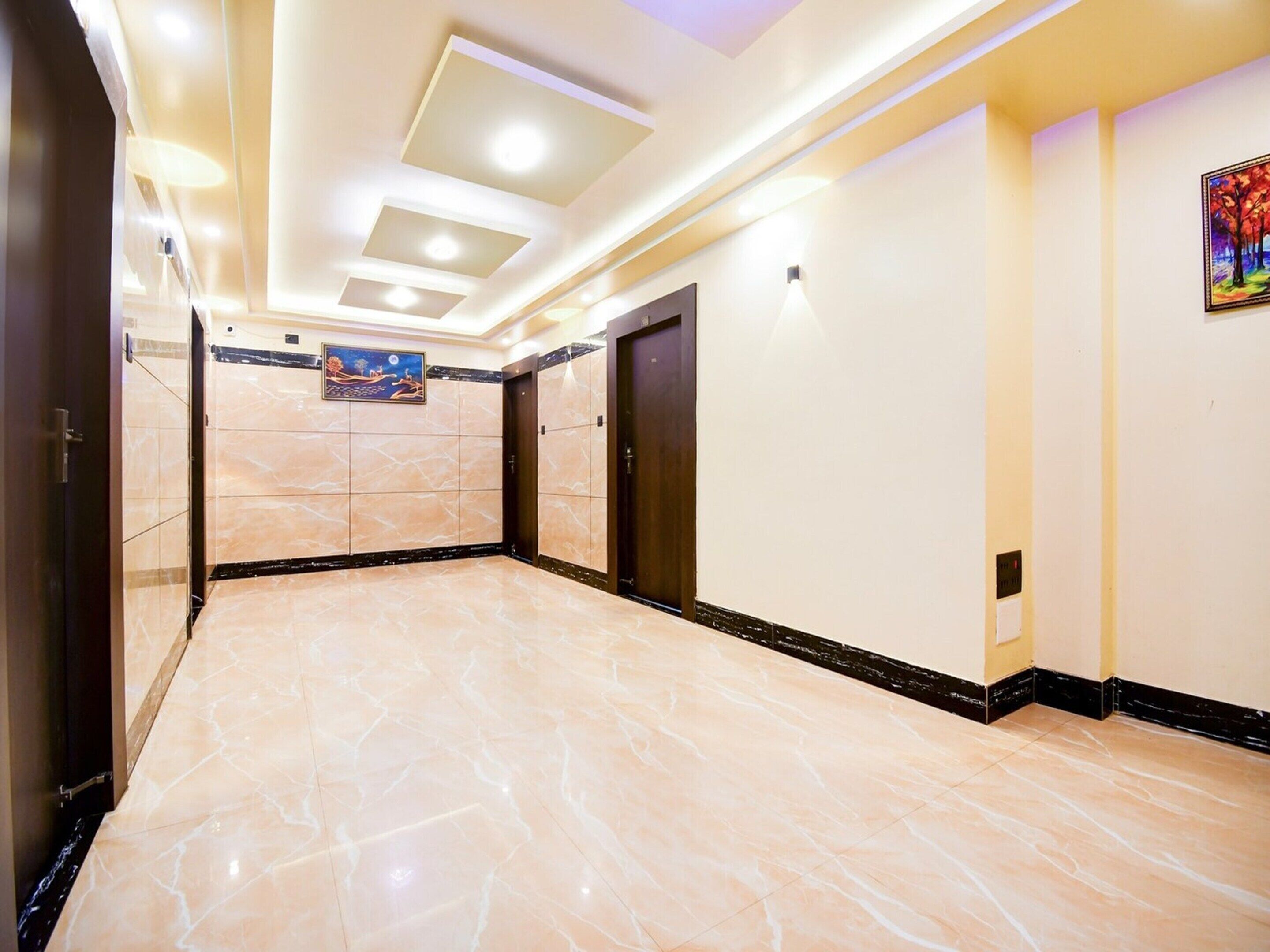 A spacious hallway with marble flooring, recessed ceiling lights, and a painting on the wall.
