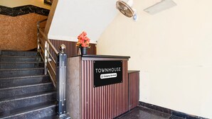 Un comptoir d’accueil avec une pancarte indiquant « TOWNHOUSE, services d’entreprise », un escalier avec une rampe et un ventilateur fixé au mur.