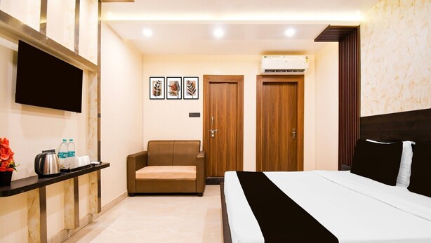 Une chambre d’hôtel équipée d’un lit, d’un canapé, d’une télévision, d’une machine à café et d’un distributeur d’eau.
