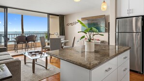 Una cocina moderna con una isla grande, electrodomésticos de acero inoxidable y vistas al océano.
