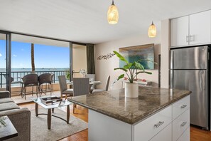 A modern kitchen with a large island, stainless steel appliances, and a view of the ocean. - SUMMER SALE! 1BD, 1BR Ocean-view getaway- Sugar Beach 215 (Kihei)