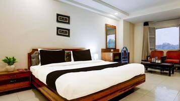 A hotel room with a large bed, bedside tables, a nightstand, a desk, a chair, a mirror, and a window with a view.