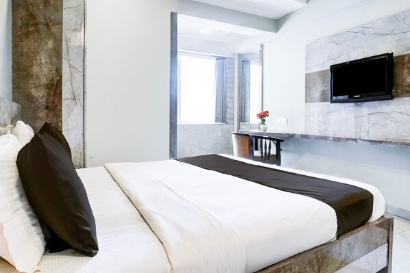 A modern hotel room with a marble bed, a flat-screen TV, and a view of the city.