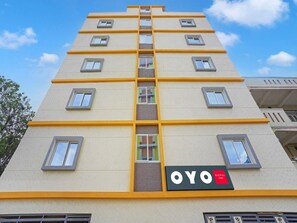 A multi-story hotel with a yellow and beige facade, multiple windows, and a sign reading 'OYO BLISSFUL STAY'. - Super Hotel O Sajapur Formerly Blissful Stays (Bengaluru)