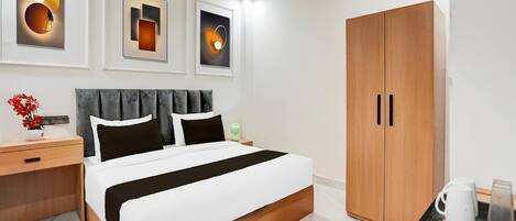 A modern hotel room with a bed, bedside tables, a wardrobe, and wall-mounted artwork.