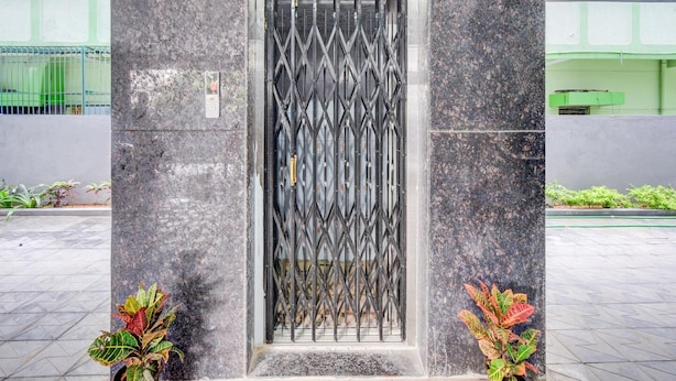 A building entrance with a metal gate, potted plants, and a tiled floor. - Premium oyo Nagaram (Hyderabad)