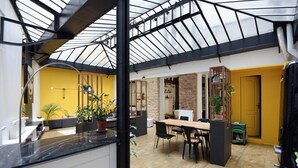 A spacious kitchen with a dining area, a yellow wall, and a brick wall. - Beautiful 3-bedroom loft in the heart of Paris (Paris)