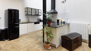 A kitchen with a black refrigerator, a potted plant, a wooden chest, and a white tiled backsplash. - Beautiful 3-bedroom loft in the heart of Paris (Paris)