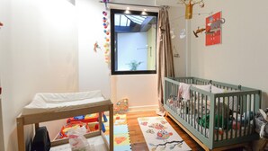 A child's room with a crib, a changing table, and a window with a view. - Beautiful 3-bedroom loft in the heart of Paris (Paris)