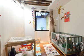 Kinderzimmer mit einem Babybett, Wickeltisch und einem Fenster mit Blick.