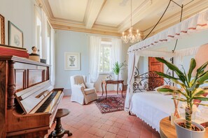 A room with a piano, a bed with a canopy, a chair, a table, and a potted plant. - Villa Near Lucca With Tuscan Garden Views (Capannori)