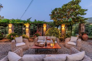 An outdoor seating area with wicker furniture, a wooden table, and string lights. - Villa Near Lucca With Tuscan Garden Views (Capannori)