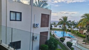 Un edificio moderno con piscina, palmeras y cielo despejado.