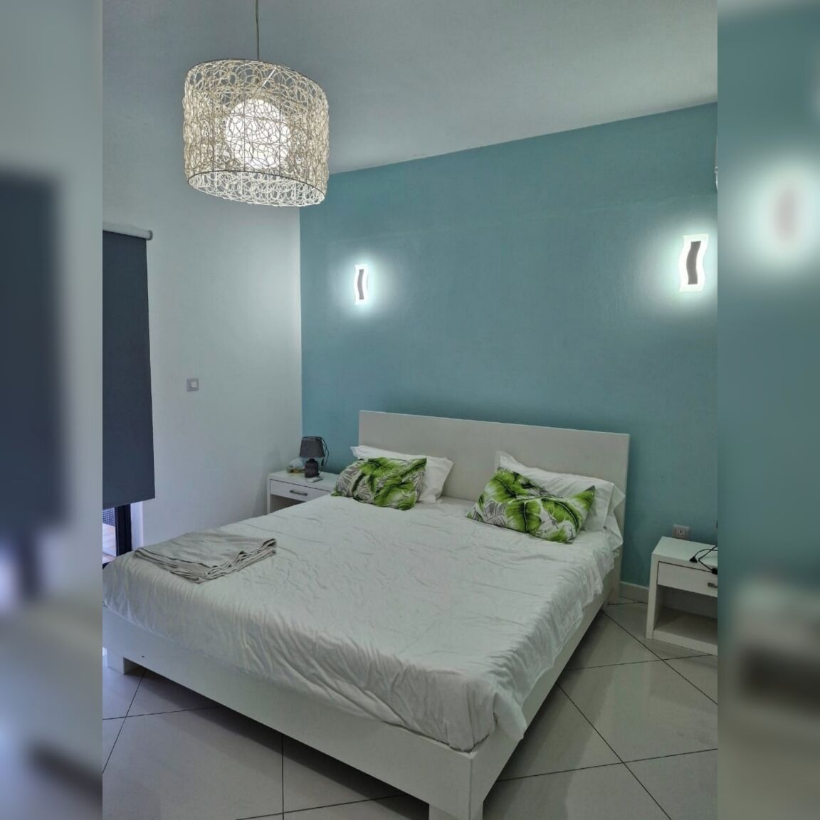 Ein modernes Schlafzimmer mit einem großen Bett, einer Pendelleuchte und einem Nachttisch mit Lampe.