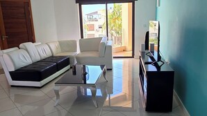 Una sala de estar con un sofá, una mesa de centro y un televisor sobre un mueble.