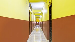 Un pasillo largo y estrecho con paredes amarillas y marrones, suelo de mármol y puertas a ambos lados.