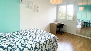 Un dormitorio con cama, escritorio, silla y un espejo grande.