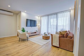 A modern living room with a sofa, armchair, and a round coffee table. - The Scandi: A Designer Dual Suite Retreat | Mt Ainslie Views (Dickson)