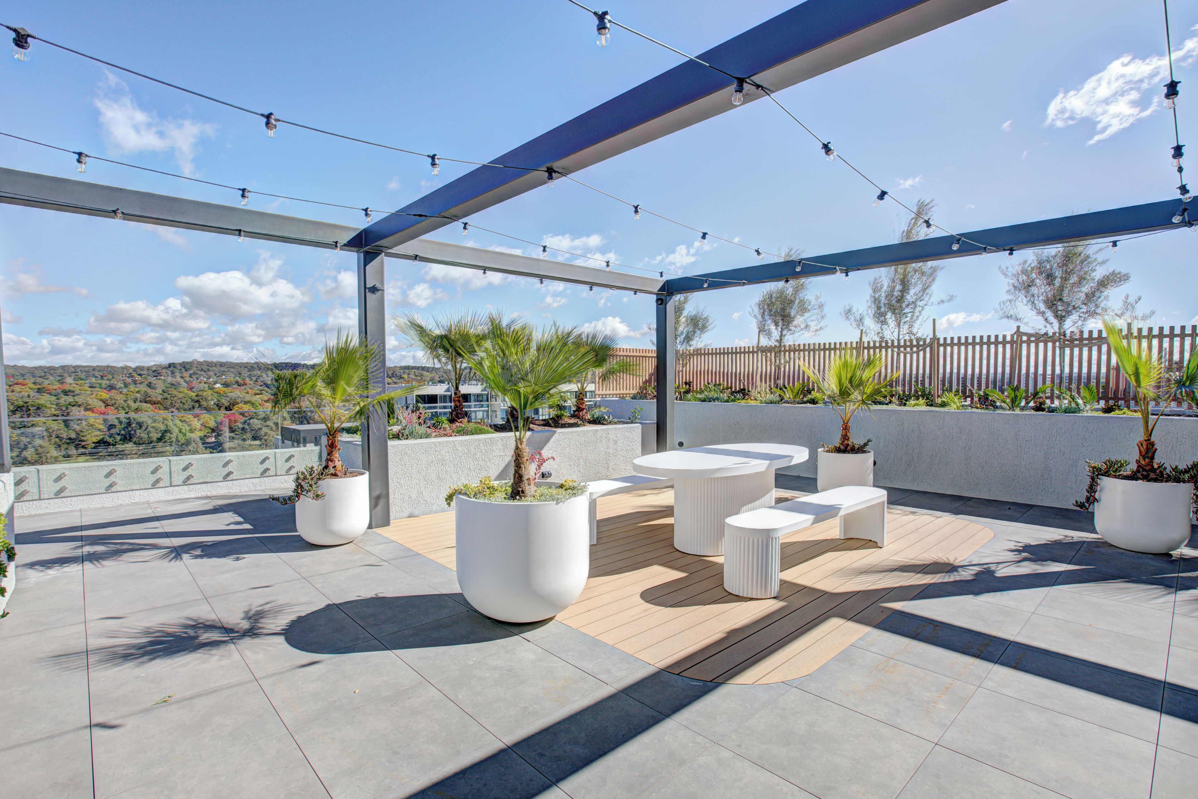 Une terrasse extérieure aménagée avec des sièges, des plantes en pot et une vue sur le paysage environnant.