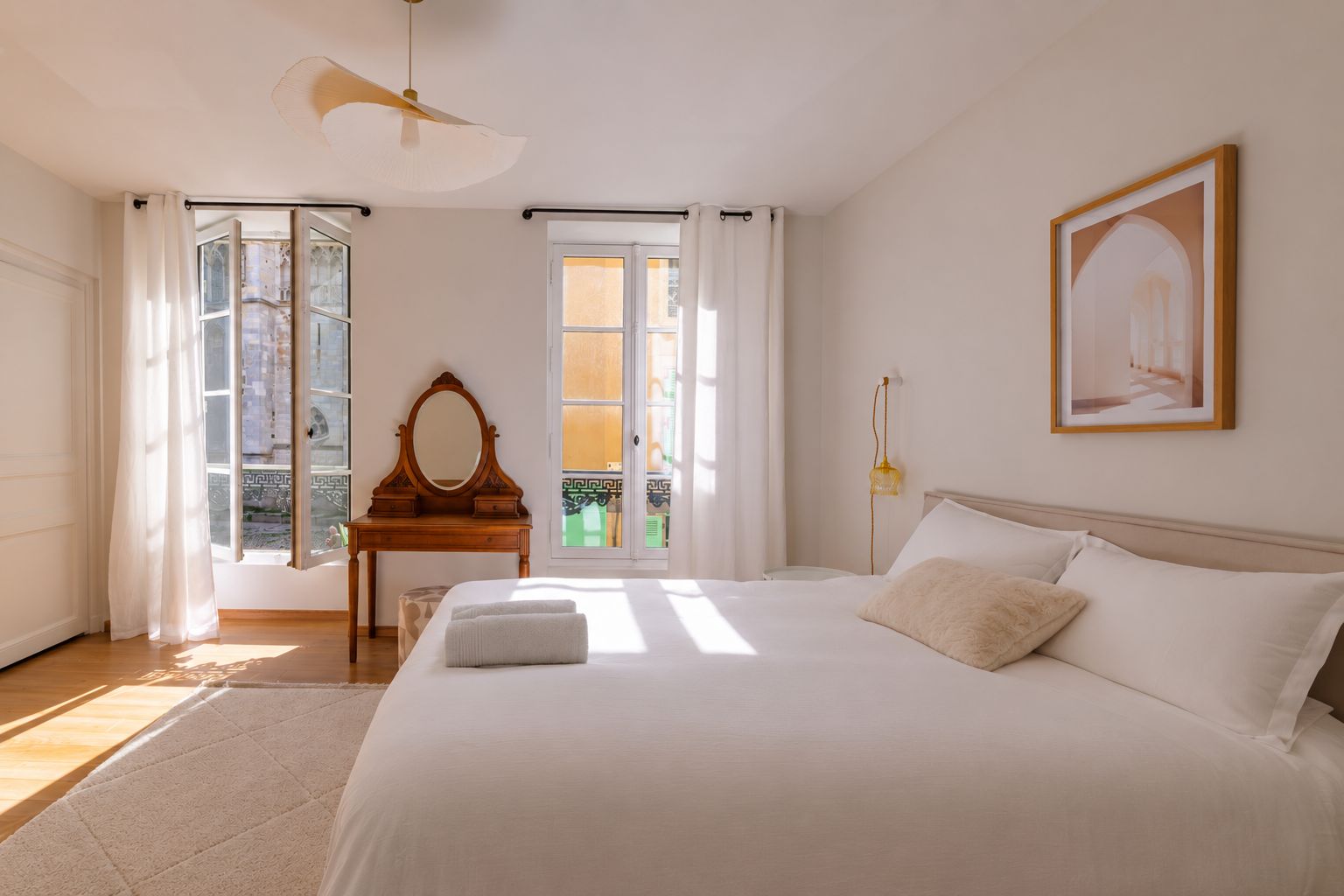 A bedroom with a large bed, a wooden dresser, a mirror, and a framed picture on the wall.