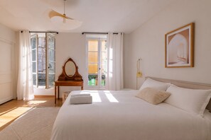 A bedroom with a large bed, a wooden dresser, a mirror, and a framed picture on the wall. - 5-Bedroom House – View of the Cathedral – Vieux Mans – Sleeps 11 (Le Mans)