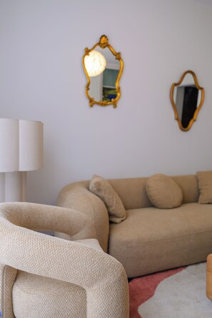 A living room with a beige sofa, a white lamp, and two wall mirrors. - 5-Bedroom House – View of the Cathedral – Vieux Mans – Sleeps 11 (Le Mans)