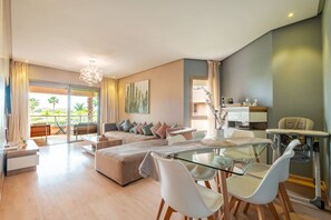 A modern living room with a glass dining table, a sofa set, and a baby changing station. - 3BR Prestigia | Pool | Parking | 12min Centre (Marrakesh)