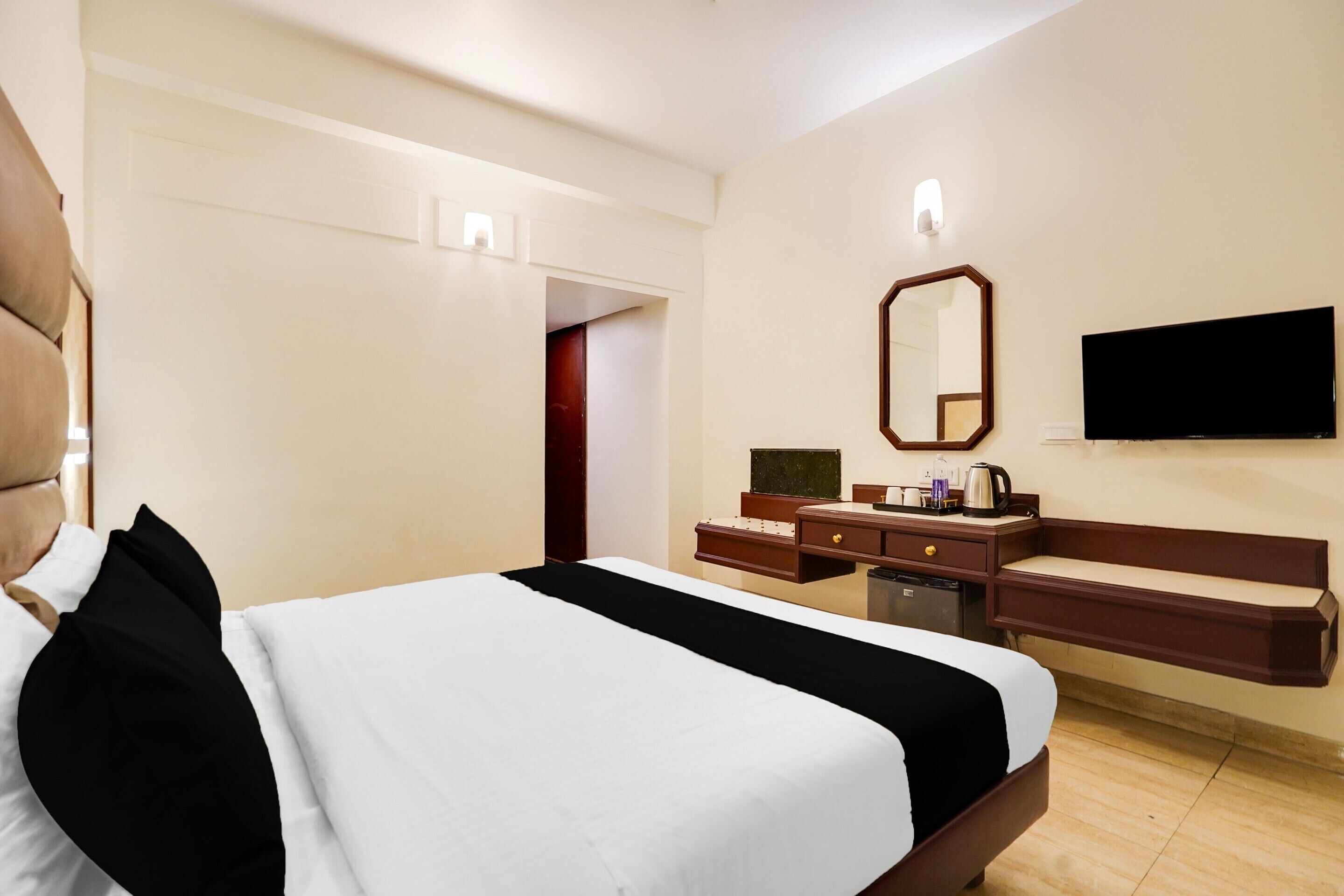 Een hotelkamer met een bed, een dressoir, een televisie en een spiegel.