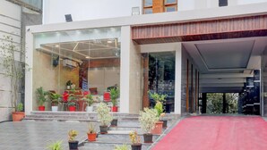 A hotel entrance with a red carpet, potted plants, and a modern glass facade. - Deluxe Sri Padmavati Ammavaari Temple Rama Grand (Tirupati)