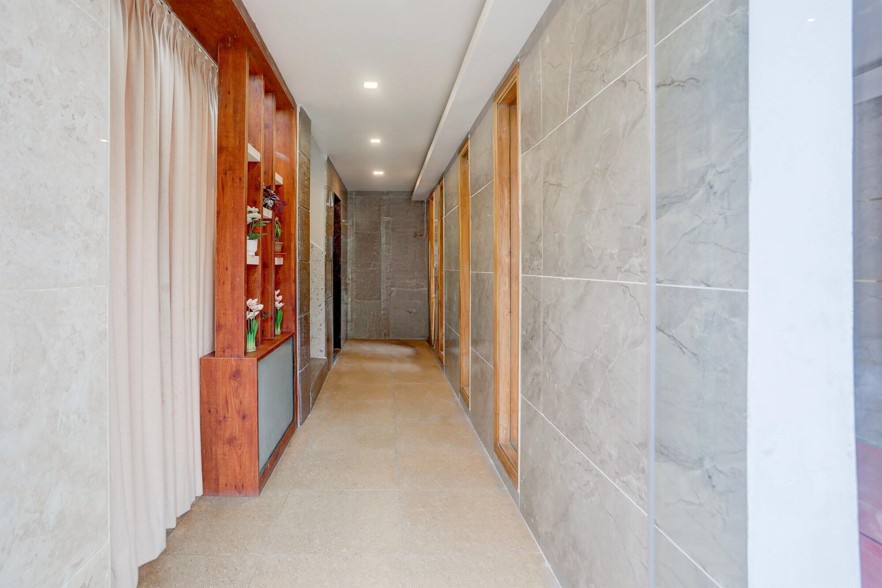 A corridor with marble walls, wooden paneling, and a tiled floor.