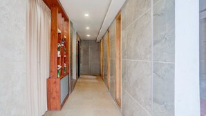 A corridor with marble walls, wooden paneling, and a tiled floor. - Deluxe Sri Padmavati Ammavaari Temple Rama Grand (Tirupati)