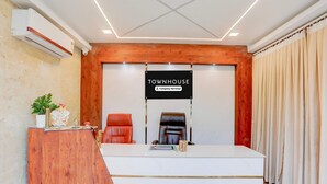 A reception area with a wooden desk, two leather chairs, a sign reading 'TOWNHOUSE Company Serviced', and a potted plant. - Deluxe Sri Padmavati Ammavaari Temple Rama Grand (Tirupati)