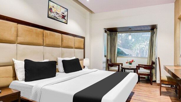 Una habitación de hotel con una cama grande, un escritorio, una silla y una ventana con cortinas.