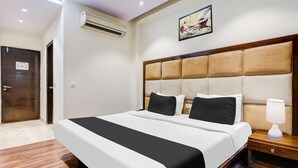 Una habitación de hotel con cama, mesita de noche, lámpara, aire acondicionado y puerta.