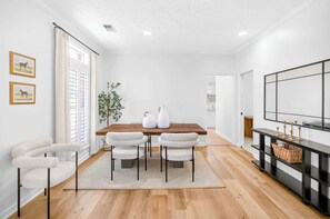 A dining area with a wooden table, four chairs, a rug, a plant, and a black console with decorative items. - Family-Friendly Home Near EastChase Shopping (Montgomery)