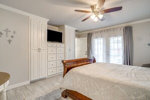 Ein Schlafzimmer mit einem Bett, einem Deckenventilator, einem Kleiderschrank und einem Fernseher.