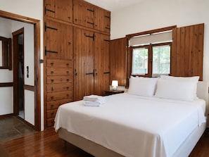 Ein Schlafzimmer mit einem Holzschrank, einem Bett mit weißer Bettwäsche und einem Nachttisch mit Lampe.
