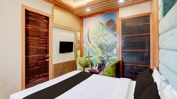 Habitación de hotel con cama, televisión de pantalla plana en la pared y un mural decorativo.