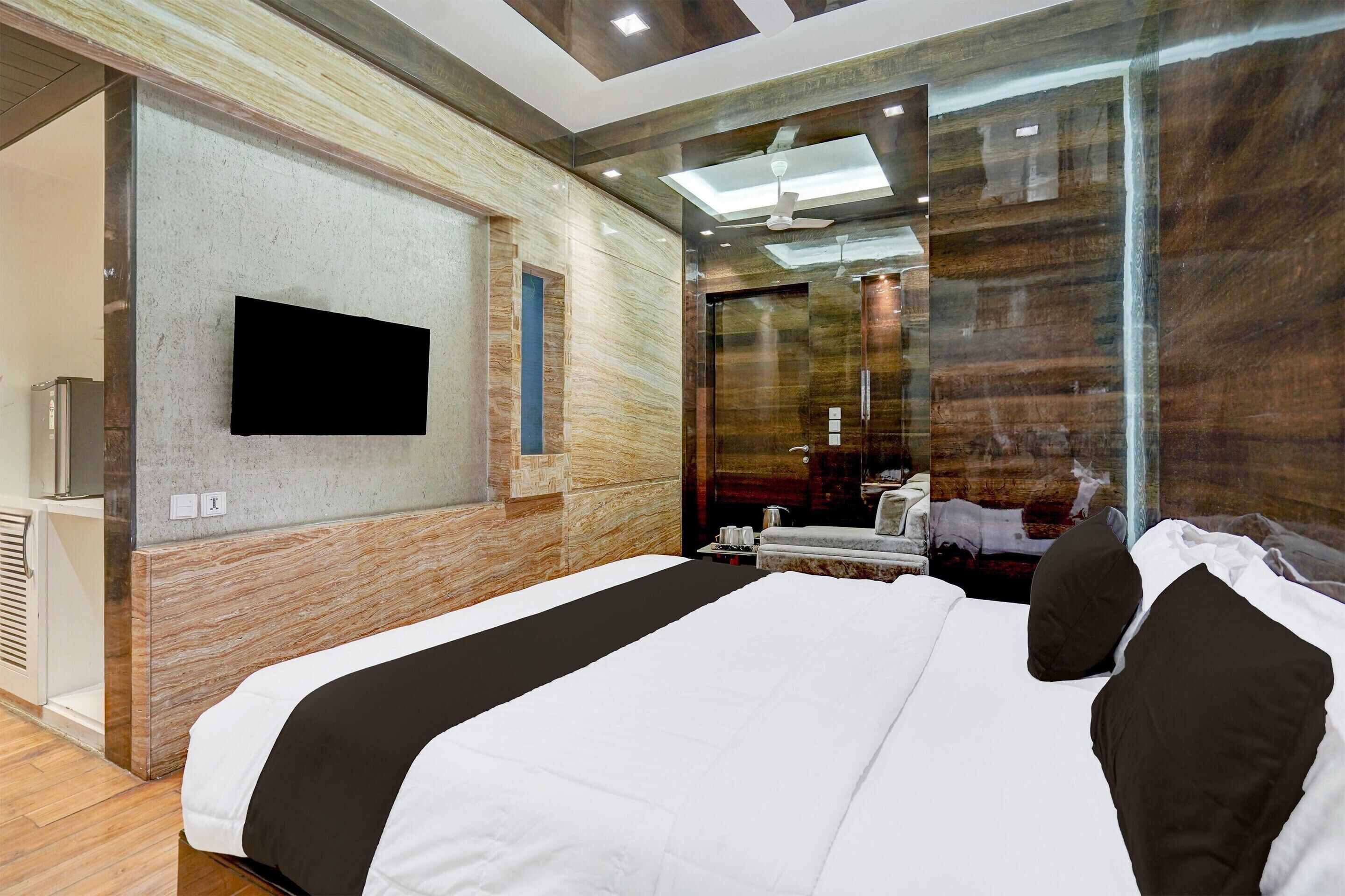 Une chambre d’hôtel moderne dotée d’un grand lit, d’un téléviseur à écran plat fixé au mur et d’un miroir qui reflète l’intérieur de la pièce.