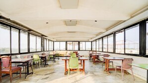 A spacious room with large windows, multiple tables and chairs, and a tiled floor.