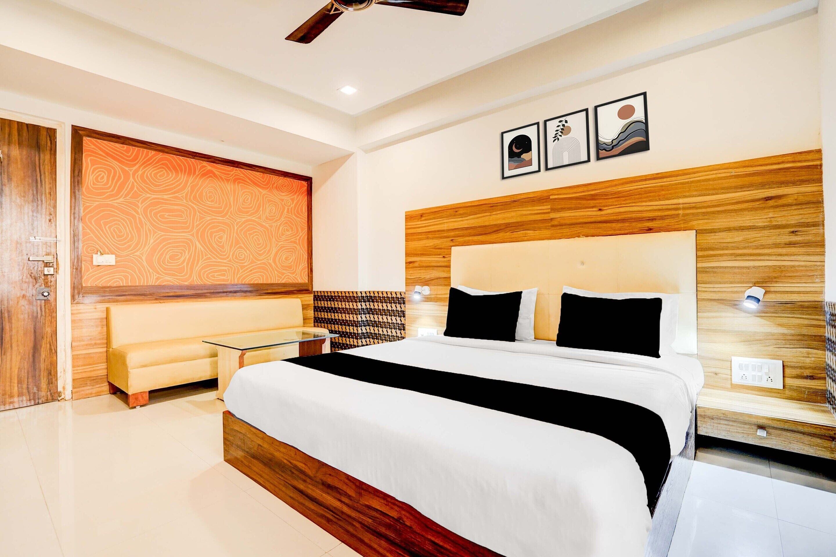 Una moderna camera d'albergo con un letto grande, un divano, un tavolino in vetro e una ventola a soffitto.