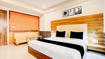Una moderna camera d'albergo con un letto grande, un divano, un tavolino in vetro e una ventola a soffitto.