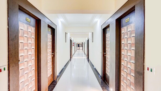 A long, narrow hotel corridor with doors on both sides, each marked with a number.
