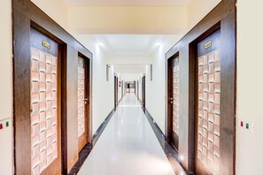 A long, narrow hotel corridor with doors on both sides, each marked with a number. - Deluxe Infocity Metrohotel Grand Krishna (Gandhinagar)
